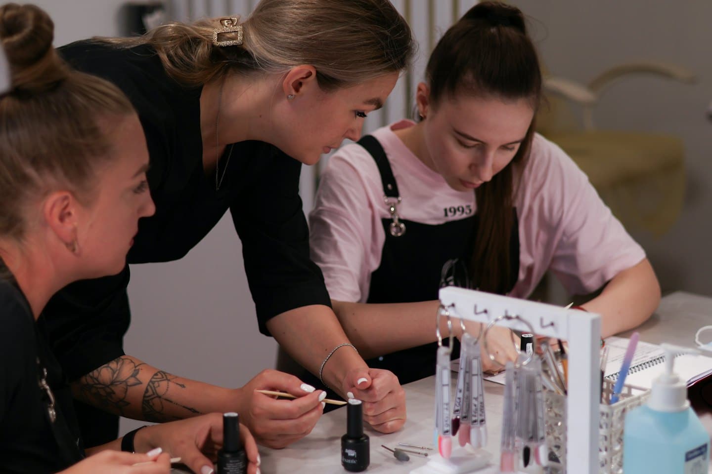 Instruktor nehtového designu předvádí techniku studentům na workshopu.